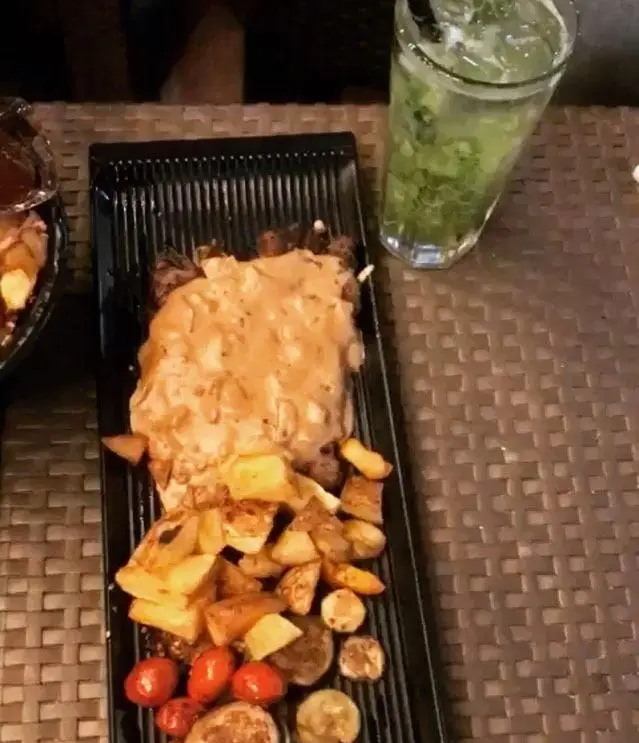 استیک لذیذ با سس قارچ، سیب زمینی تنوری و گوجه گیلاسی در کافه رد. همراه با موهیتو خنک برای تجربه ای دلنشین.