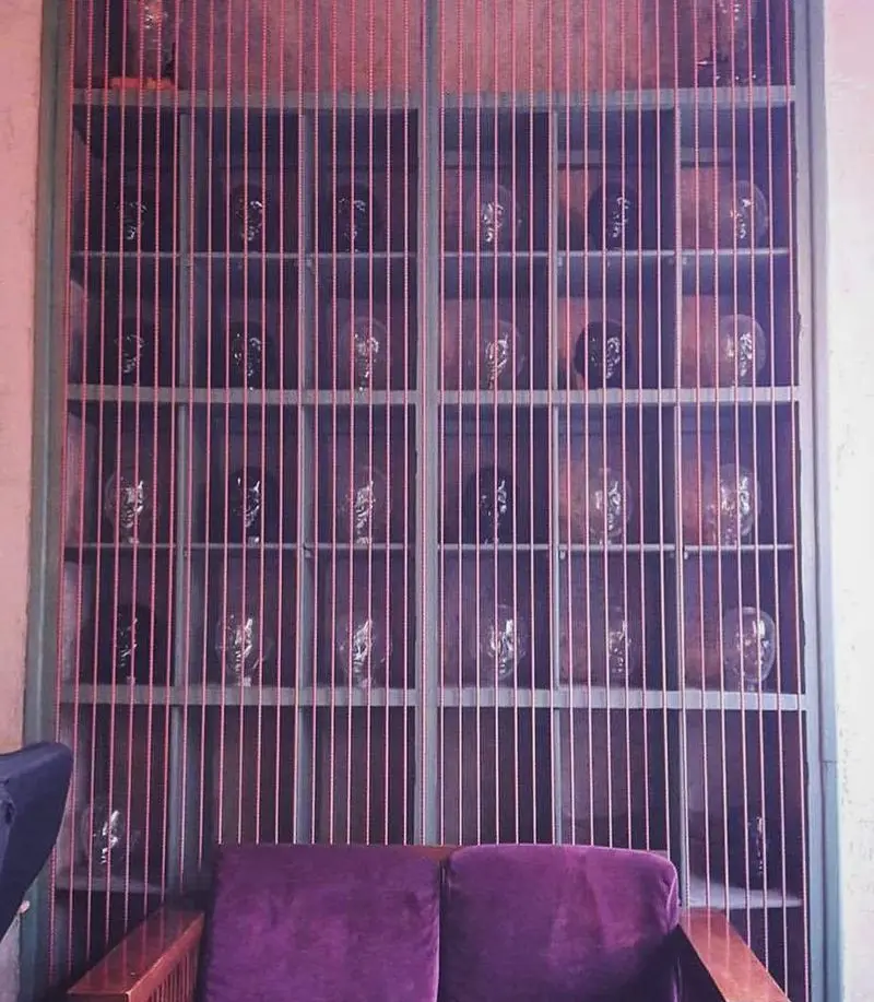 دکوراسیون داخلی خاص کافه رد با پنجره دکوراتیو، پرده آویز میله‌ای، شلف‌های متعدد و صندلی مخملی بنفش برای فضایی دلنشین و مدرن.