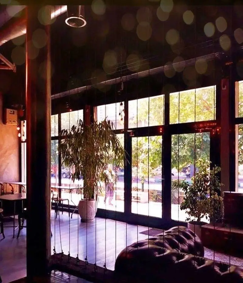 فضای داخلی دنج و دلنشین کافه رد با پنجره های بزرگ رو به فضای سبز شهری، مبلمان راحت و طراحی مدرن برای یک تجربه لذت بخش.