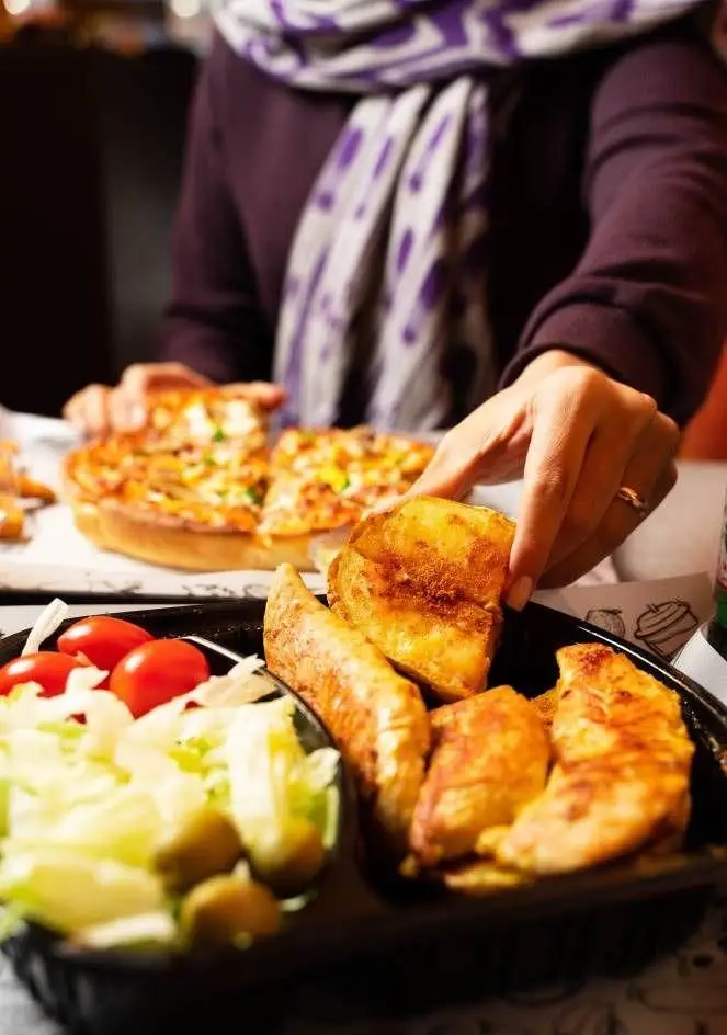 سفره‌ای خوش رنگ در دیب چیز سعادت آباد: مشتری با دست غذا برمی‌دارد. پیتزا، سالاد تازه، سیب زمینی و مرغ گریل شده.