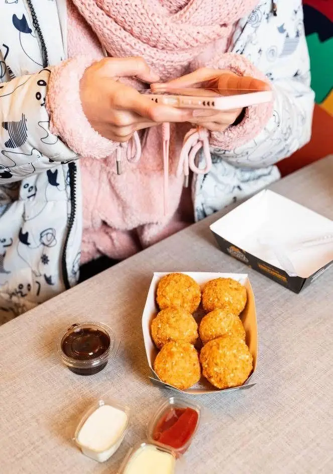 تجربه دلپذیر در دیب چیز شعبه سعادت آباد: مشتری مشغول سفارش غذای مورد علاقه خود، در کنار توپک‌های پنیری سوخاری و سس‌های خوشمزه.