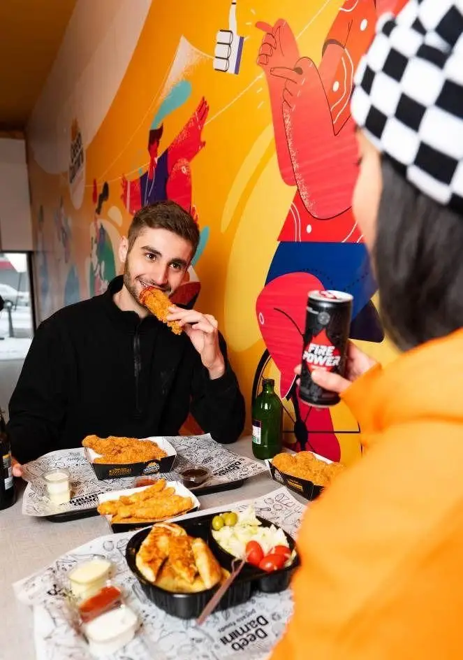 زوجی جوان از غذای خوشمزه دیب چیز شعبه سعادت آباد لذت می‌برند؛ مرغ سوخاری ترد، سس‌های متنوع و نوشیدنی انرژی‌زا در فضایی دلنشین.