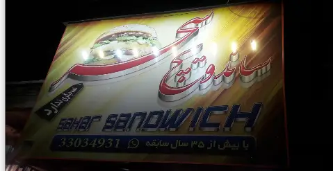 تابلوی تبلیغاتی ساندویچ سحر با تصویر همبرگر جذاب، نام کسب و کار Sahar Sandwich، شماره تماس و سابقه بیش از ۳۵ سال فعالیت در فست فود.