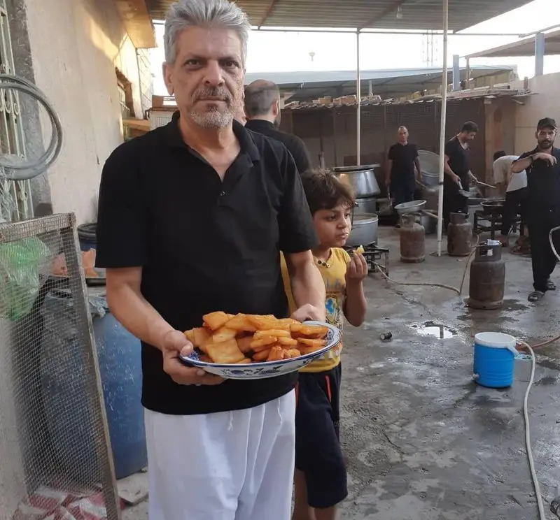 تصویری از مردی در حال سرو غذای گرم فلافل ابوحیدر، در محیطی محلی و پویا، همراه با کودکی و فعالیت های آشپزی.