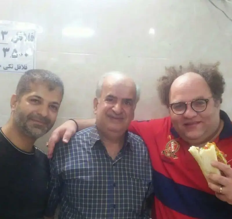 سه مشتری شاد در فلافل ابوحیدر در حال لذت بردن از ساندویچ‌های فلافل با کیفیت عالی و محیط گرم و صمیمی رستوران.