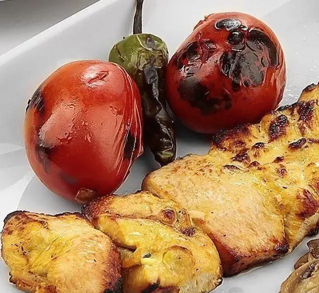 تصویری از جوجه کباب طلایی و آبدار رستوران نایب ابان، سرو شده با گوجه و فلفل کبابی، یک غذای اصیل و دلپذیر ایرانی.