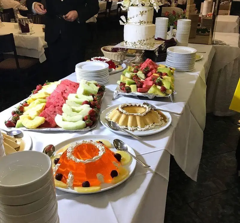 بوفه دسر شیک رستوران نایب ابان با کیک عروسی دو طبقه، میوه‌های تازه مانند هندوانه و توت فرنگی، ژله و کرم کارامل.