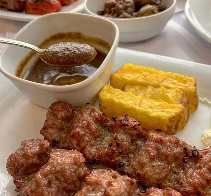 کباب کوبیده لذیذ رستوران نایب ابان با سس قهوه‌ای مخصوص سرو شده در کاسه و سیب زمینی سرخ شده طلایی، غذای اصیل ایرانی.