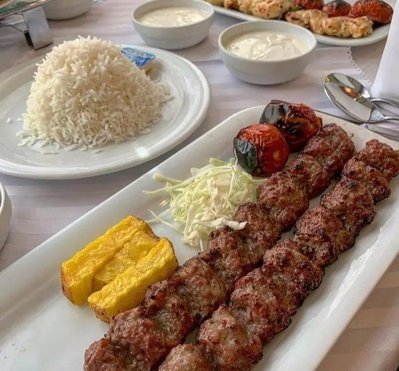 کباب کوبیده به همراه برنج و گوجه کبابی در رستوران نایب ابان، یک غذای اصیل ایرانی آماده سرو. تجربه لذت بخش در نایب ابان.