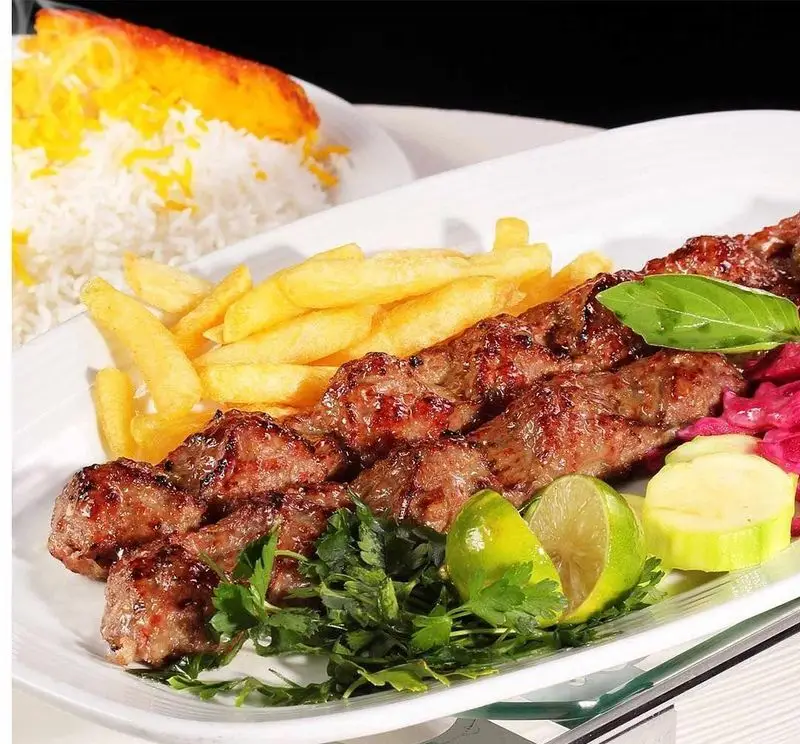 عکس کباب کوبیده مخصوص رستوران نایب ابان، همراه با چلو زعفرانی، سیب زمینی سرخ کرده و مخلفات تازه. غذای خوشمزه ایرانی برای ناهار و شام.