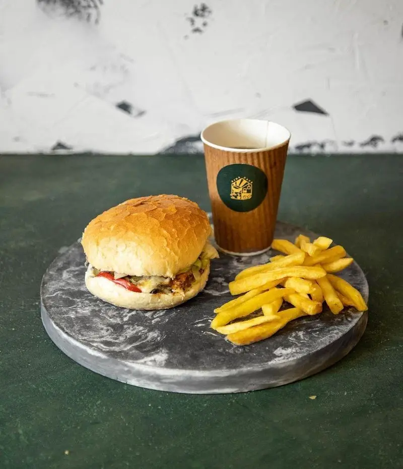 همبرگر آبدار کافه آجنا با نان برشته، سیب زمینی سرخ کرده طلایی و نوشیدنی گرم، منوی فست فود ایده‌آل برای سفارش.