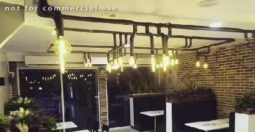 نمایی از دکوراسیون داخلی جذاب پیتزا سیب ۳۶۰ با نورپردازی صنعتی لوله ای، دیوار آجری و محیطی مدرن و دلنشین برای تجربه غذایی لذت بخش.