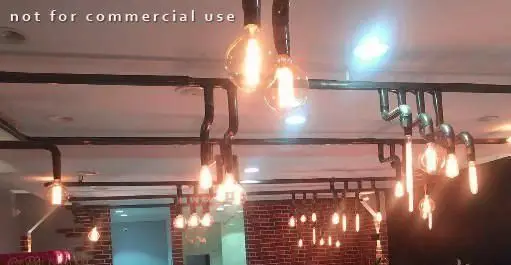 دکوراسیون داخلی جذاب و نورپردازی صنعتی رستوران پیتزا سیب ۳۶۰ با لامپ‌های ادیسونی و لوله‌های فلزی. محیطی گرم و دلنشین.