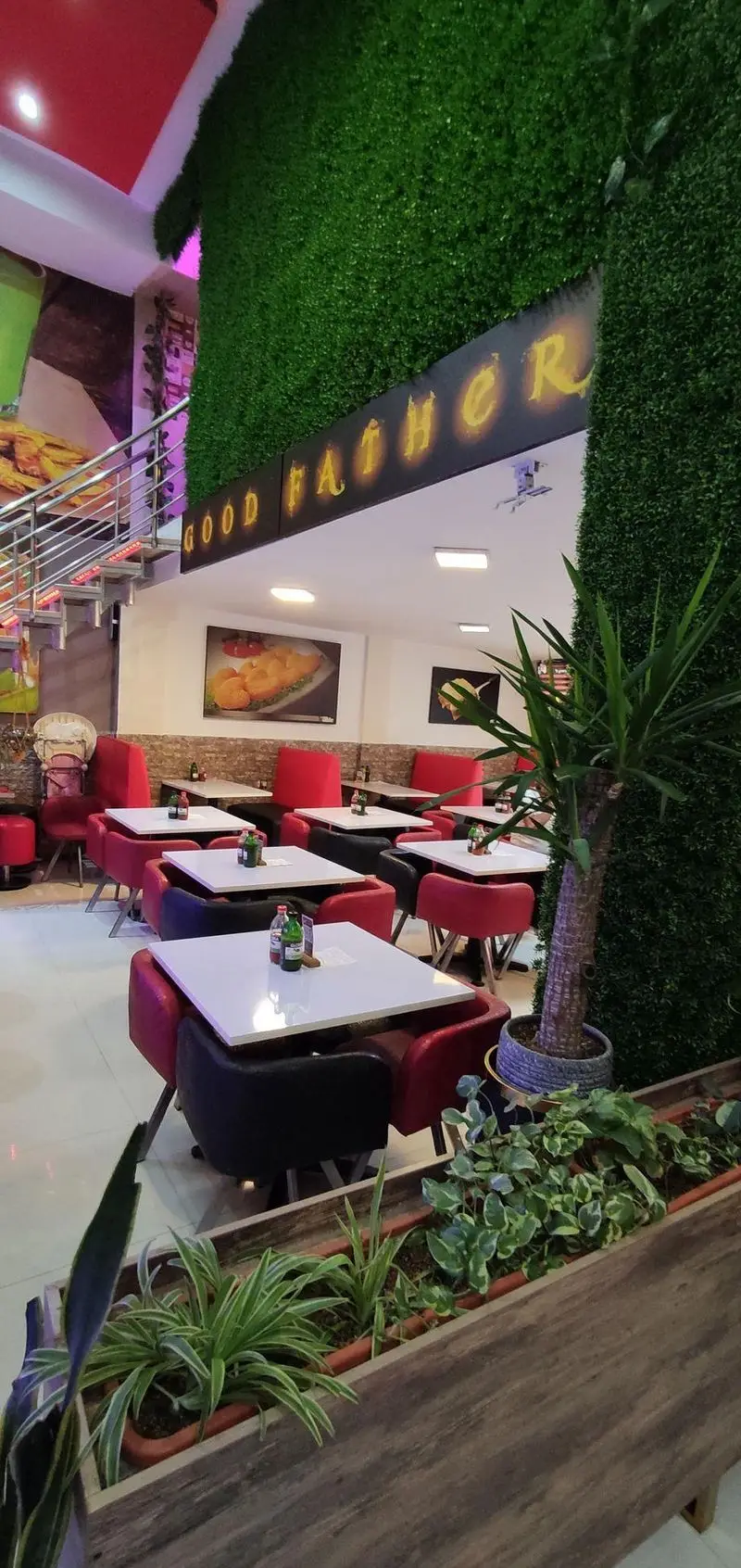 فضای داخلی مدرن و دلنشین فست فود پدرخوب با دیوارهای سبز، میز و صندلی‌های قرمز و سیاه. مکانی عالی برای صرف غذا.