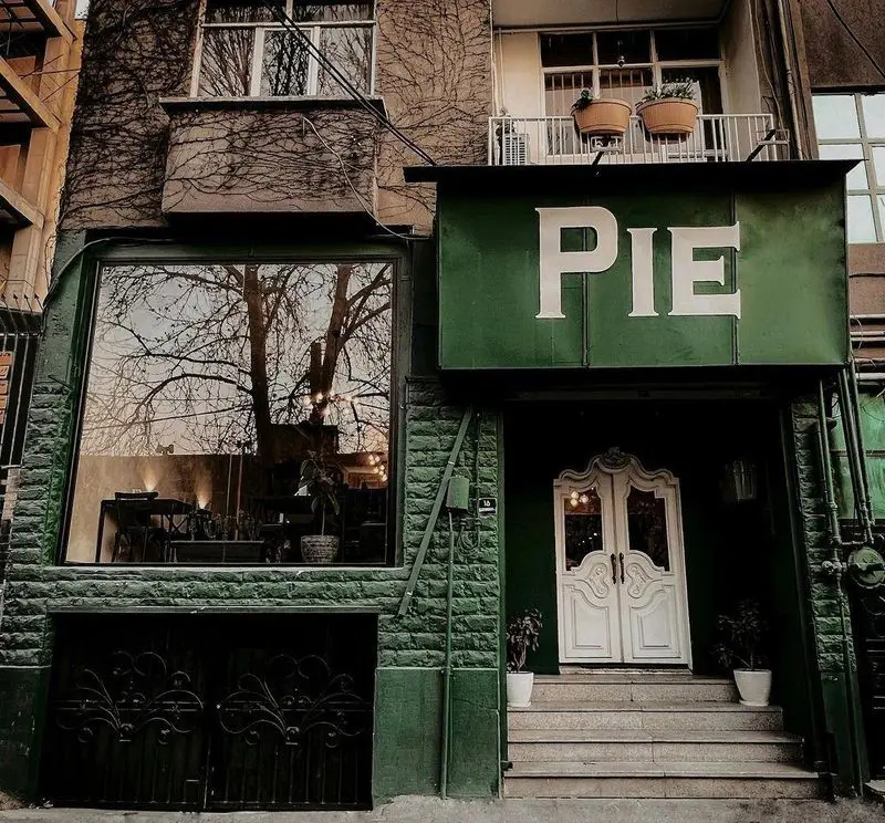 نمای بیرونی ساختمان کافه و رستوران پیتزا پای، با طراحی مدرن و رنگ سبز جذاب، شامل پنجره بزرگ و درب ورودی سفید کلاسیک.