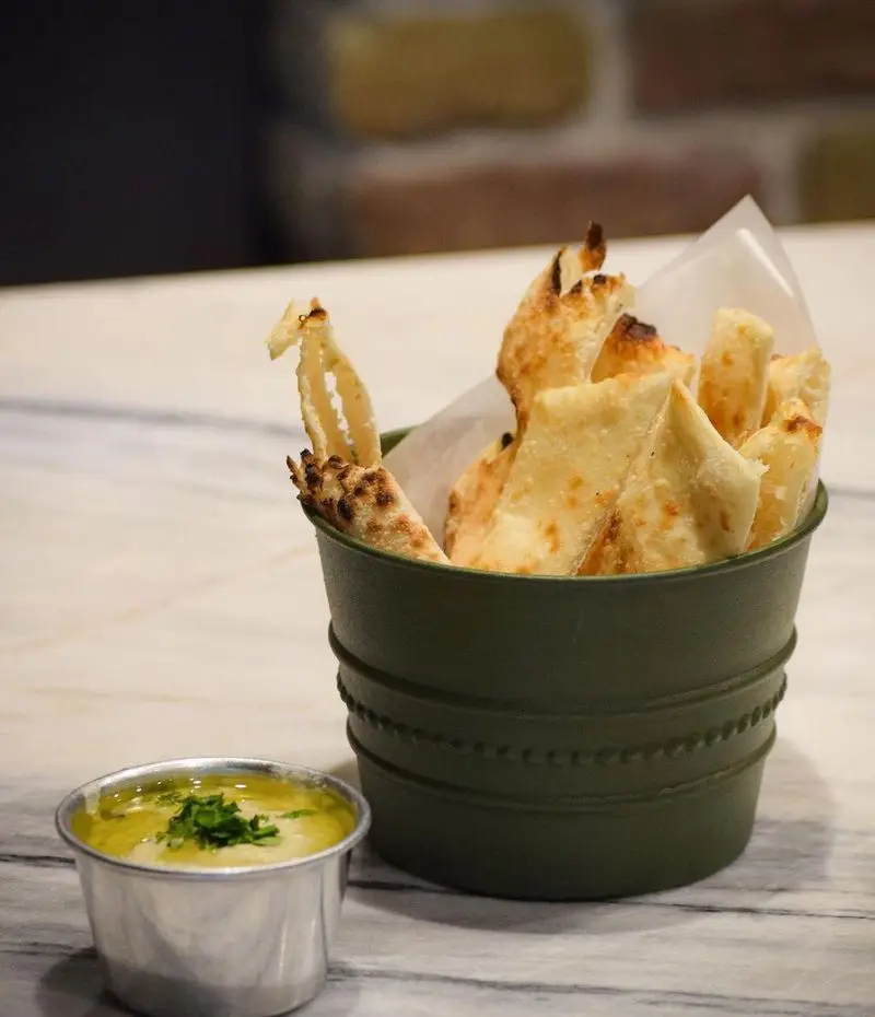 نان پیتزای ترد و تازه پخته شده با رنگ طلایی و سس مخصوص پیتزا پای در ظرفی شیک، پیش غذایی اشتهاآور در رستوران.