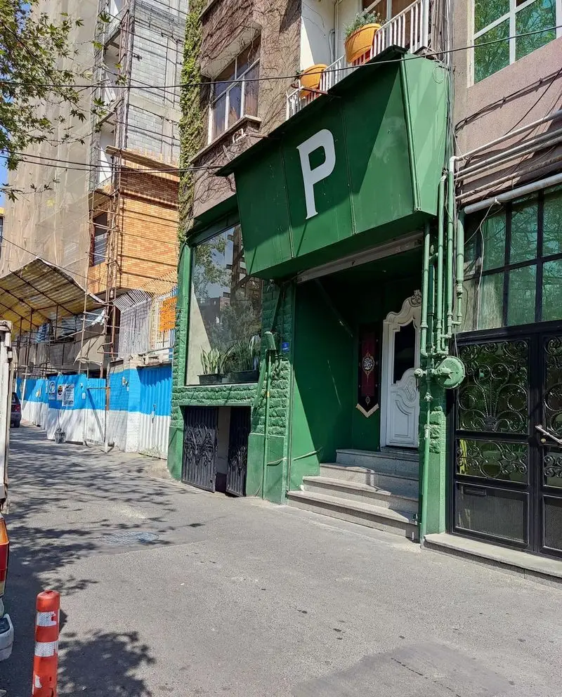 نمای خارجی رستوران پیتزا پای، شامل سردر سبز رنگ بزرگ با حرف P، درب ورودی با پله و پنجره‌های شیشه‌ای در محیطی شهری