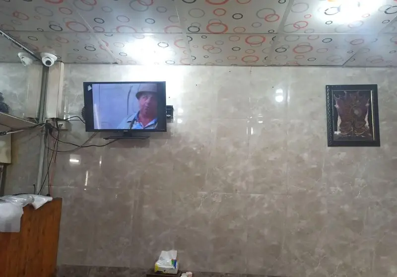 فضای داخلی فست فود مددی با دیوارپوش سرامیکی، سقف طرح‌دار، تلویزیون دیواری و تزئینات. محیطی دلنشین برای مشتریان.