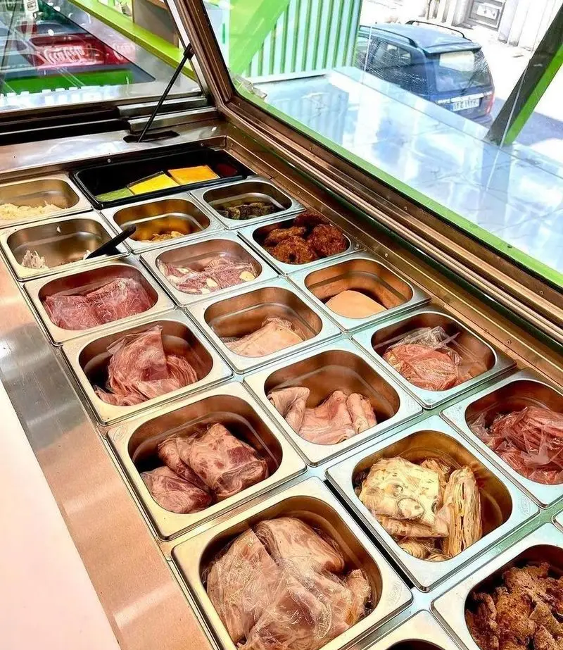 ویترین فست فود پک مک با انواع مواد اولیه تازه و باکیفیت ساندویچ، شامل کالباس، گوشت‌های فرآوری شده، پنیر و مخلفات.
