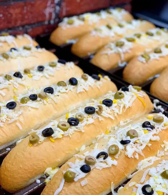ردیفی از نان‌های تازه پخته شده با پنیر فراوان، زیتون سیاه و سبز، آماده در فست فود پک مک. غذایی دلپذیر برای تجربه ای متفاوت.
