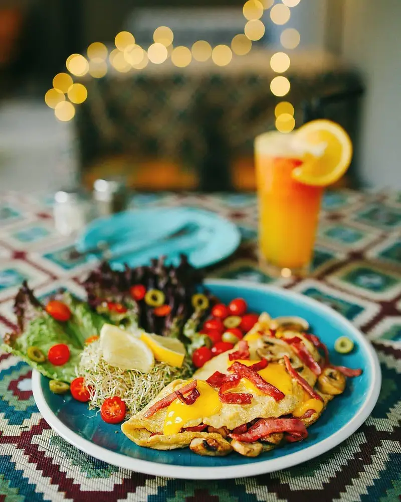 صبحانه خوشمزه و رنگارنگ در کافه ث شامل املت، سالاد تازه، نوشیدنی میوه ای، تجربه‌ای شیک و دلپذیر برای مشتریان.