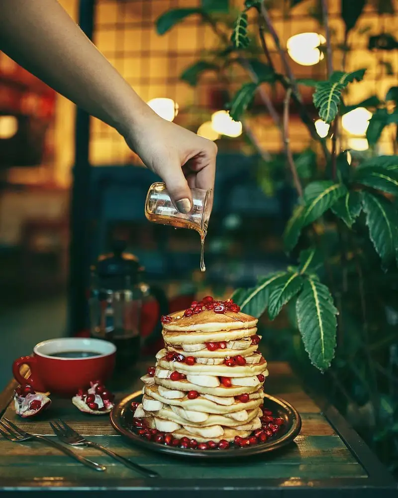 پنکیک لذیذ با موز، انار و سیروپ در کافه ث، بهترین صبحانه و دسر در فضایی دلنشین. تجربه طعم بی نظیر در کافی شاپ ث.