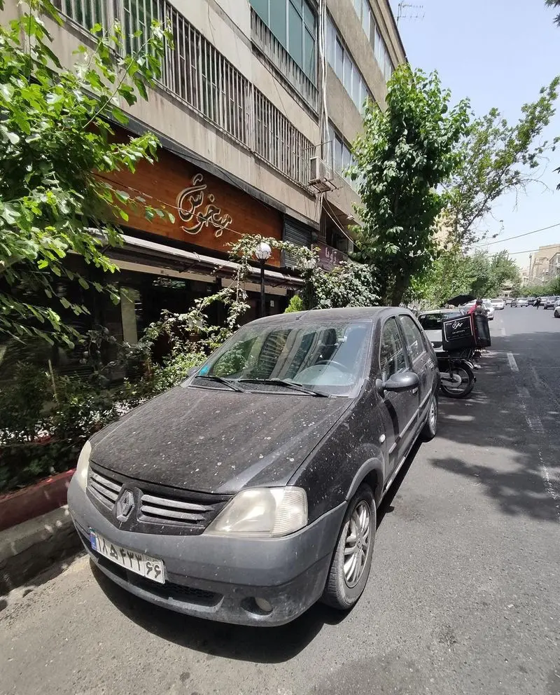 نمای بیرونی رستوران فست فود پیتزا میخوش در یک روز آفتابی، با تابلوی چوبی زیبا و درختان سرسبز، و یک خودروی رنو مشکی پارک شده جلوی آن.