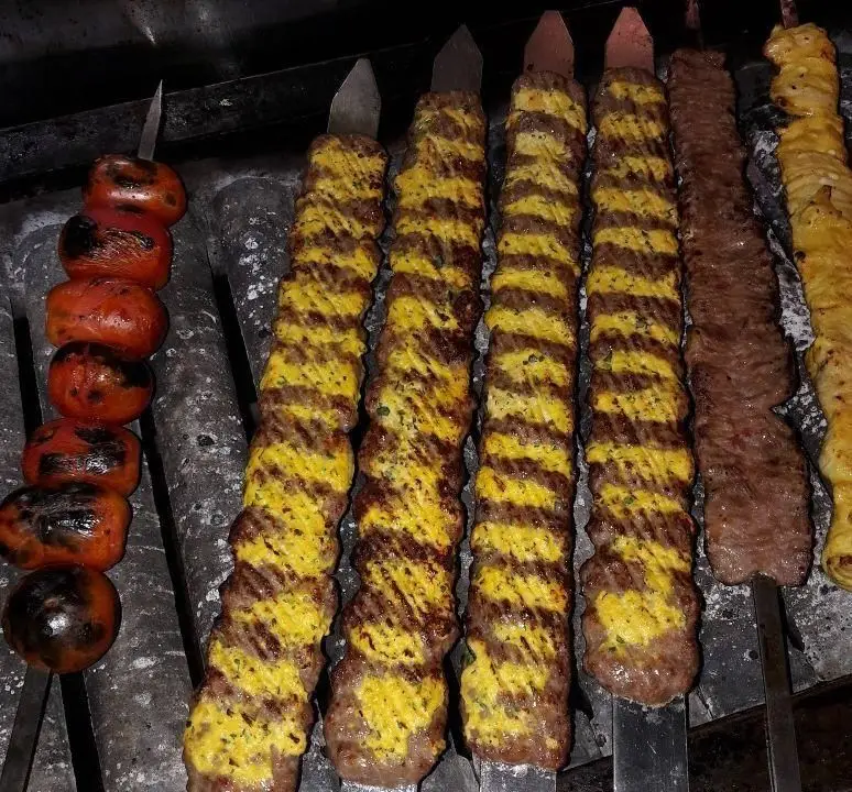 انواع کباب ایرانی شامل کوبیده، جوجه و کباب‌های مخصوص زعفرانی با گوجه کبابی در حال پخت روی منقل در سالن غذاخوری برادران میلاد۲.