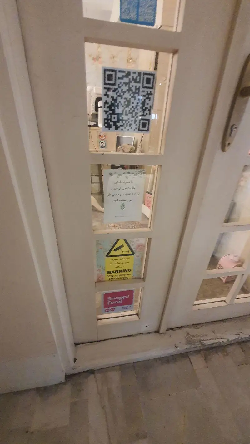 درب شیشه‌ای ورودی رستوران گیاهی پیور با QR کد سفارش، اطلاعیه تخفیف ماگ شخصی، اخطار دوربین مداربسته و لوگوی اسنپ فود.