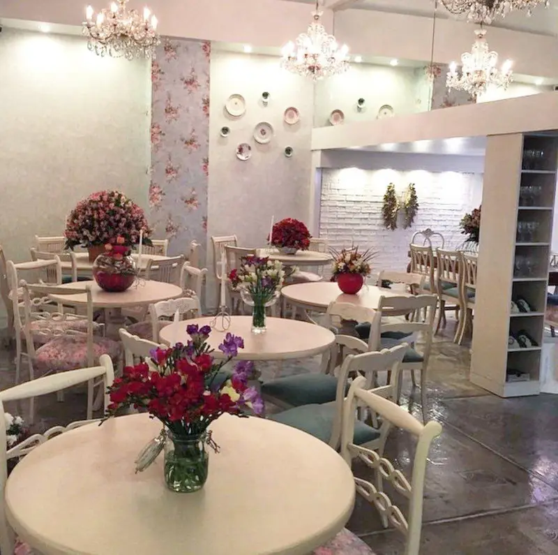 فضای داخلی و دکوراسیون شیک و دلنشین رستوران گیاهی پیور با میزهای گرد، صندلی‌های سفید، گل‌آرایی زیبا و لوسترهای کریستال.