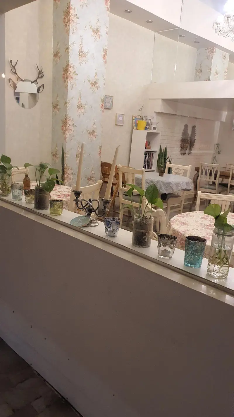 فضای داخلی دنج و دلنشین رستوران گیاهی پیور با دکوراسیون گلدار، گیاهان سبز، شمع‌ها و آینه‌های تزئینی، آماده پذیرایی از مهمانان.