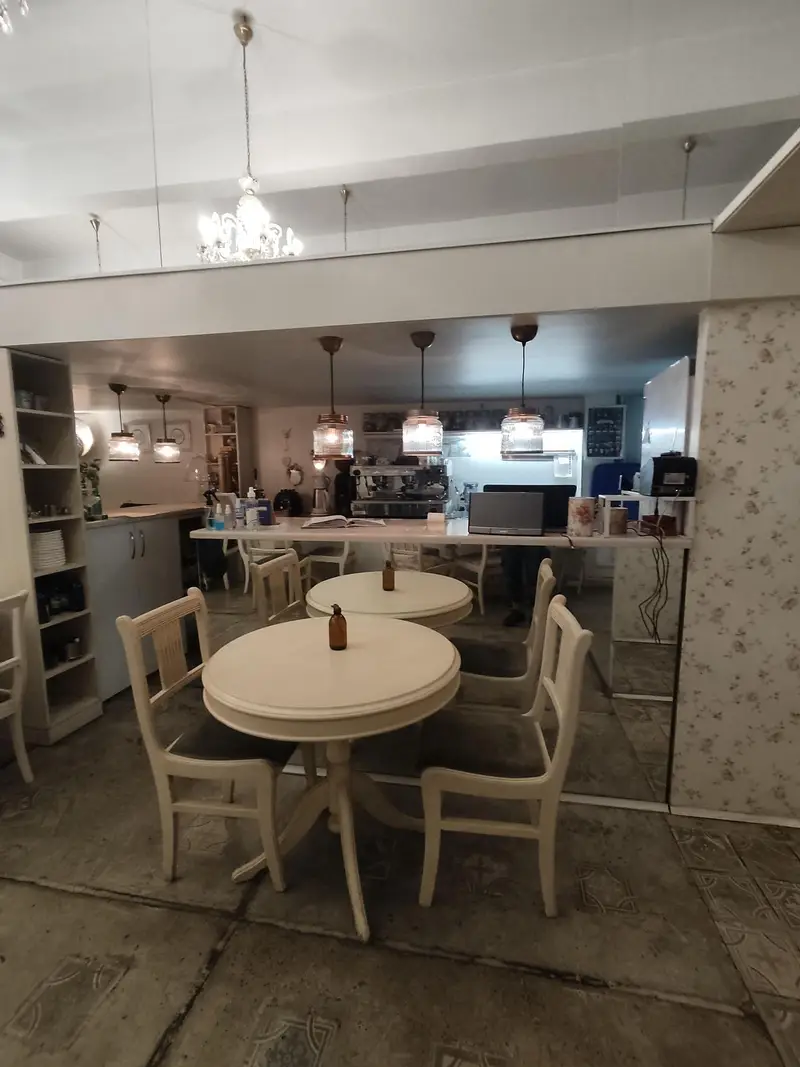 نمایی از داخل رستوران گیاهی پیور با چیدمان میز و صندلی‌های سفید، پیشخوان سرو و نورپردازی گرم، محیطی دلپذیر برای مشتریان.