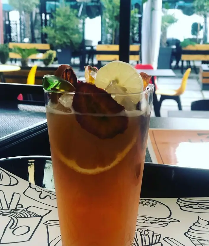 نوشیدنی فصلی و دلپذیر کافه لوپو: کوکتل میوه‌ای سرد با لیمو، پرتقال و توت فرنگی خشک در محیط زیبای کافه.