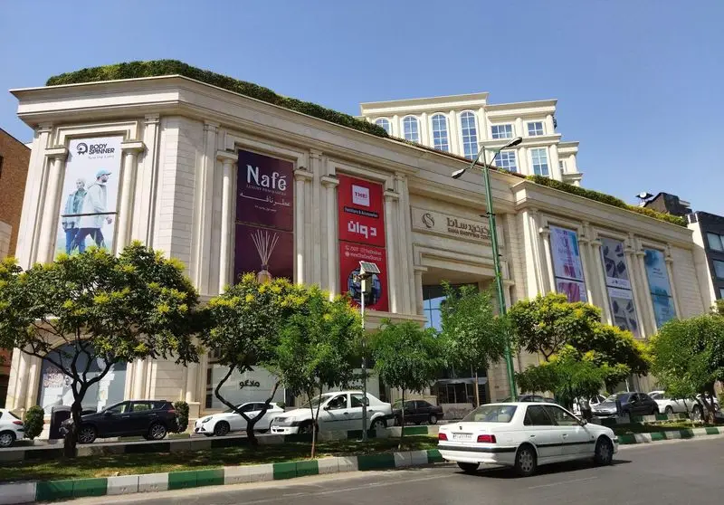 نمای خارجی فودکورت چیکولند سانا، یک مرکز خرید لوکس و مدرن با فروشگاه‌های متنوع، درختان سرسبز و خودروها در خیابان.