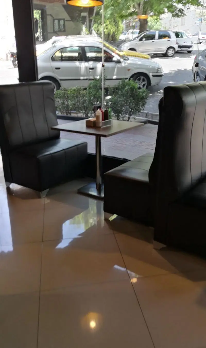 فضای داخلی دنج و مدرن فست فود پیله با میز و صندلی‌های راحت و منظره‌ای زیبا از خیابان، ایده‌آل برای صرف غذا.