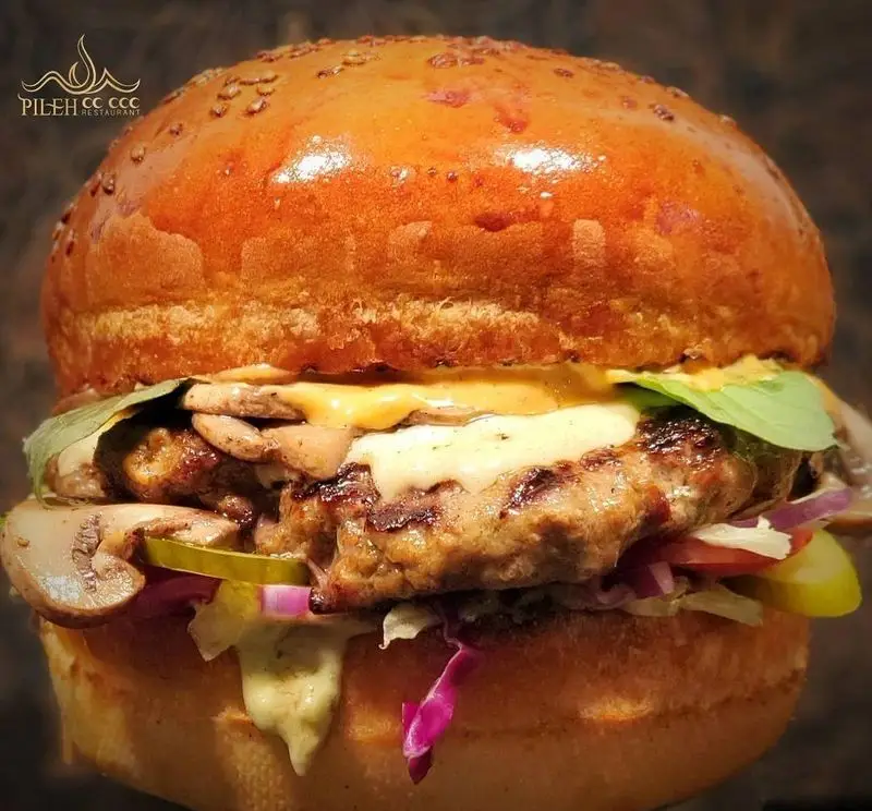 همبرگر لذیذ و پرملات فست فود پیله با نان طلایی، پتی گوشت، قارچ، پنیر آب شده، کاهو، پیاز، خیارشور و سس مخصوص.