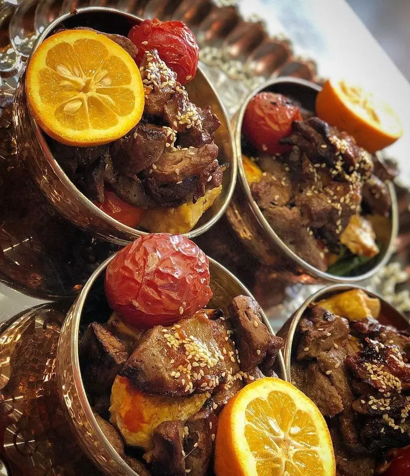 کباب و جگر سرای عمو هوشنگ: کباب‌های لذیذ با گوجه کبابی، پرتقال اسلایس شده و کنجد در ظروف مسی، آماده در رستوران.
