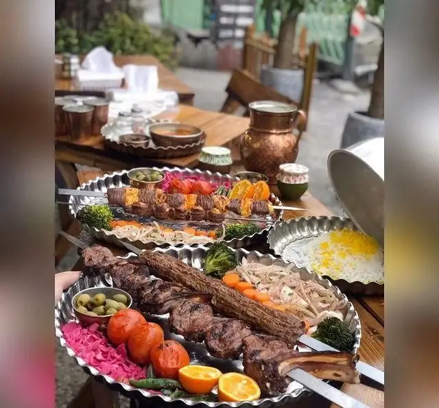 میز شاهانه کباب‌های لذیذ عمو هوشنگ شامل شیشلیک، کوبیده، جوجه کباب و کباب برگ با مخلفات متنوع و برنج زعفرانی، تجربه‌ای اصیل از غذای ایرانی.