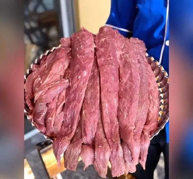 سینی بزرگ گوشت تازه راسته، آماده برای طبخ کباب‌های خوشمزه و باکیفیت در کباب و جگر سرای عمو هوشنگ.