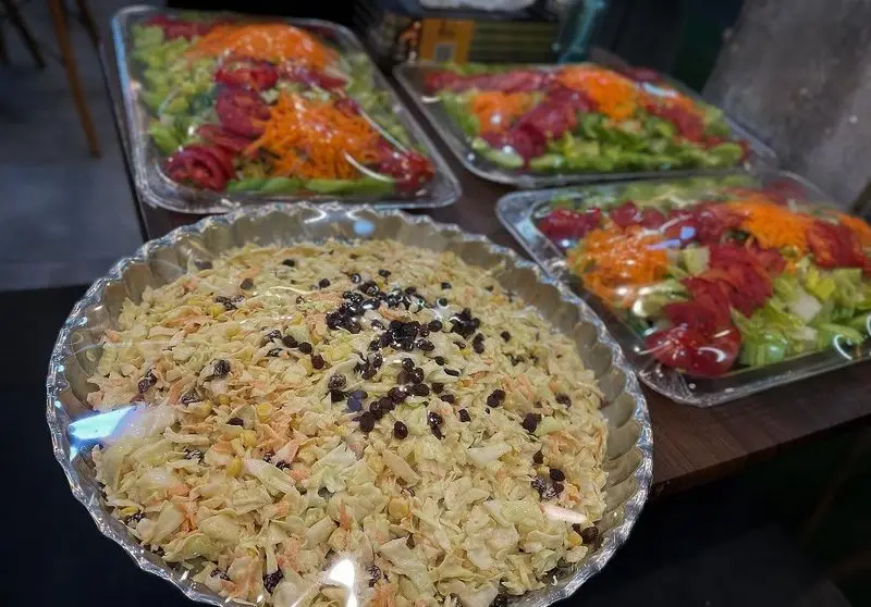 سالادهای تازه و رنگارنگ کباب و جگر سرای عمو هوشنگ شامل سالاد کلم با کشمش، ذرت و هویج و سالاد کاهو و گوجه برای غذای آماده.