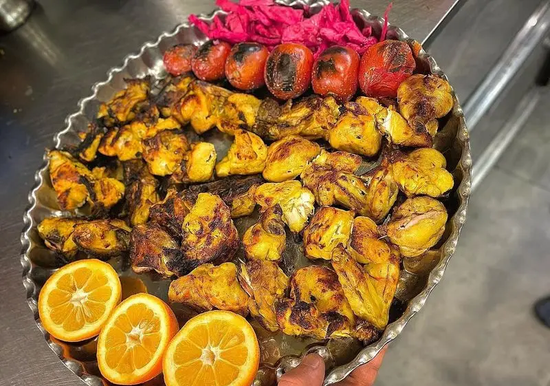 سینی جوجه کباب زعفرانی و لذیذ عمو هوشنگ با گوجه کبابی، ترشی و پرتقال تازه. بهترین تجربه غذای ایرانی در کبابی عمو هوشنگ.