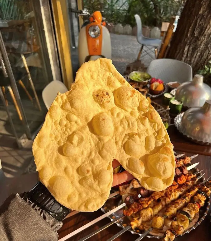 نمایی اشتهاآور از کباب و جگر سرای عمو هوشنگ، جایی که مشتری از نان تافتون داغ با کباب‌های متنوع و خوش‌طعم ایرانی لذت می‌برد.