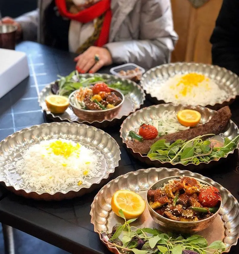 تجربه غذای اصیل ایرانی در کباب و جگر سرای عمو هوشنگ: کباب کوبیده، برنج زعفرانی و خورشت لذیذ با چیدمان زیبا در ظروف مسی.