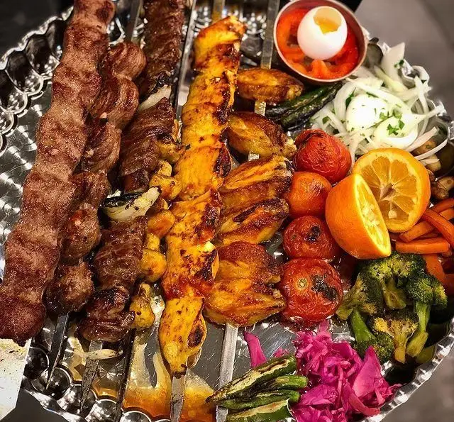 سینی کباب عمو هوشنگ شامل کوبیده، جوجه و میکس گوشت با گوجه کبابی، پیاز، پرتقال، کلم و مخلفات تازه. غذای خوشمزه و سنتی ایرانی.