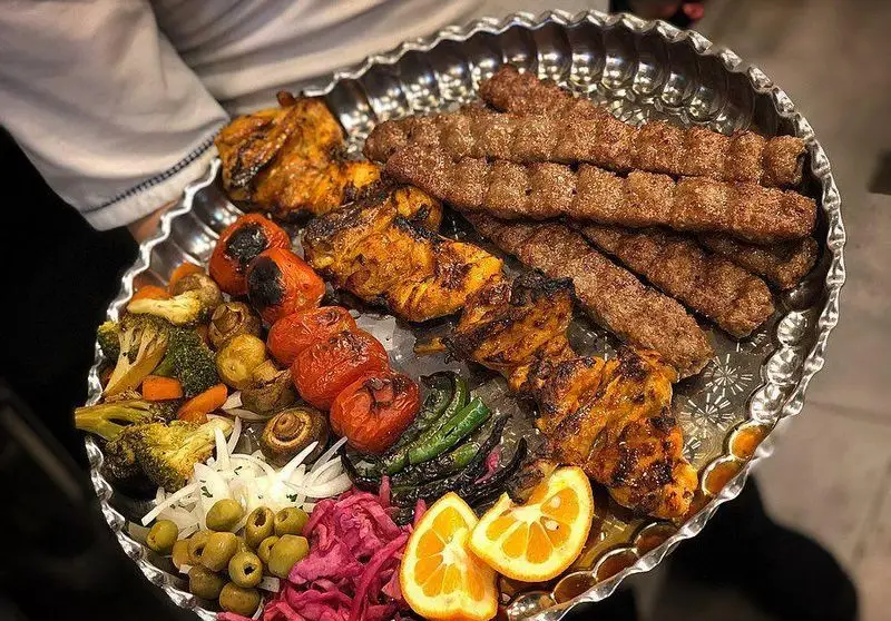 سینی کباب عمو هوشنگ شامل کوبیده و جوجه کباب در کنار گوجه، فلفل، قارچ، سبزیجات، زیتون و ترشی. تجربه لذیذترین غذای ایرانی.