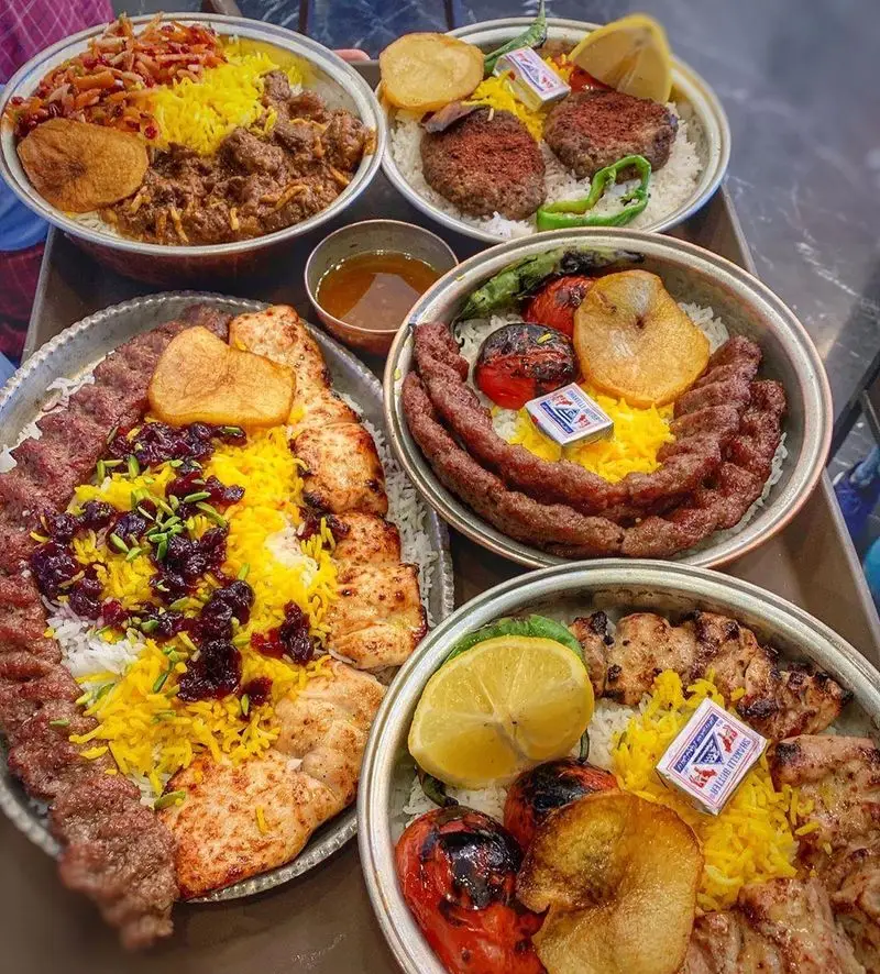 سینی پر از غذاهای اصیل و خوشمزه ایرانی؛ شامل کباب کوبیده، جوجه کباب، خورش و چلو با برنج زعفرانی از رستوران اصیل