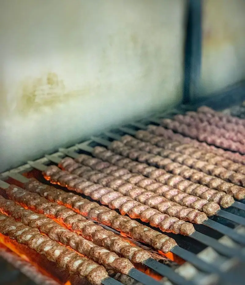 رستوران اصیل: کباب کوبیده تازه و لذیذ در حال گریل شدن روی منقل داغ ذغالی. طعم اصیل غذای ایرانی را تجربه کنید.