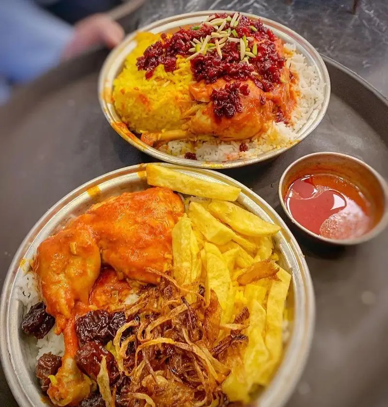 دو بشقاب چلو مرغ سنتی و لذیذ رستوران اصیل. زرشک پلو با مرغ و خلال پسته و چلو مرغ با پیاز داغ و سیب زمینی سرخ کرده.