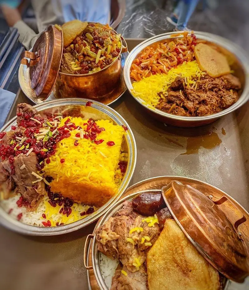 تصویر غذاهای لذیذ ایرانی رستوران اصیل: زرشک پلو با گوشت و ته دیگ‌های طلایی، سرو شده در دیگچه‌های سنتی و پرطرفدار.