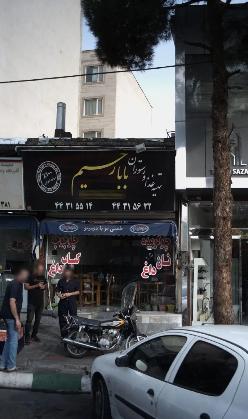 تصویر بیرونی تهیه غذا و رستوران بابا رحیم با تابلو مشکی و زرد، ارائه دهنده چلوکوبیده، کباب و نان داغ با برنج ۱۰۰٪ ایرانی. شماره تماس جهت سفارش موجود است.